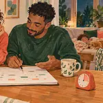 Two co-parents review a weekly calendar together beside a small timer