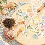Illustration of overhead view of a child and caregiver arranging colourful blank word cards into imaginative branching paths on a round table