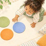 Overhead illustration of a child noticing three large felt circles on a mat.
